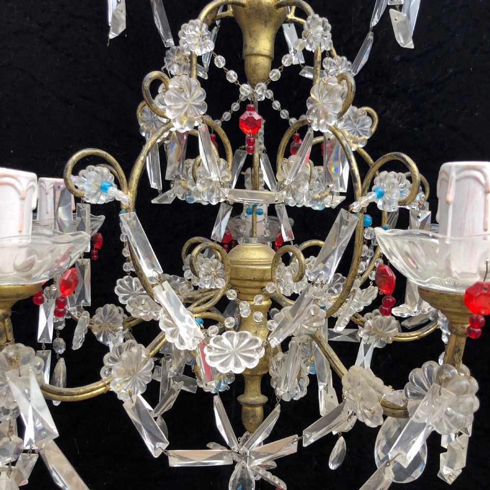 A five-light Florentine chandelier featuring a gilt metal frame adorned with clear crystal drops, floral glass rosettes, and coloured accent beads. View IV