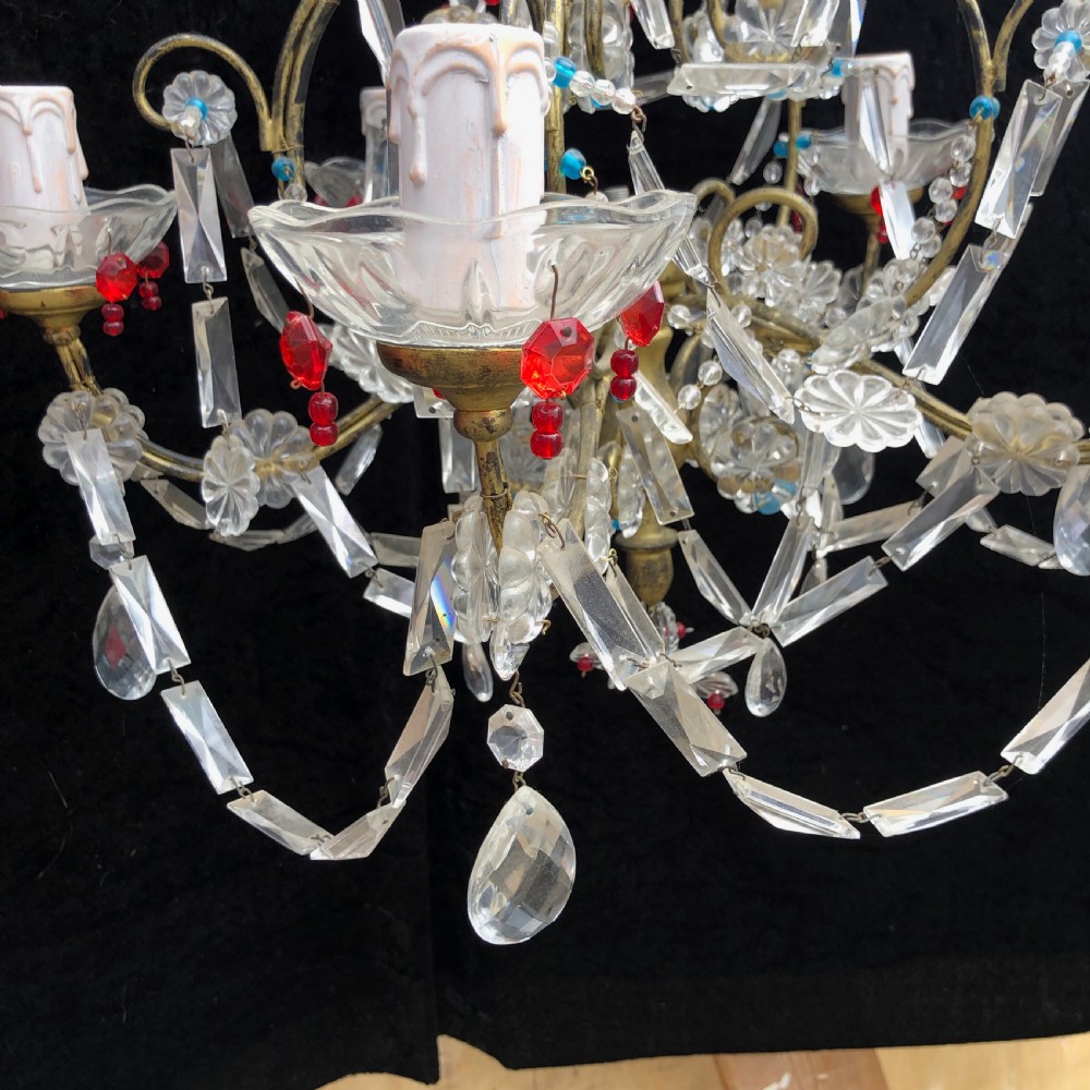 A five-light Florentine chandelier featuring a gilt metal frame adorned with clear crystal drops, floral glass rosettes, and coloured accent beads. View VI
