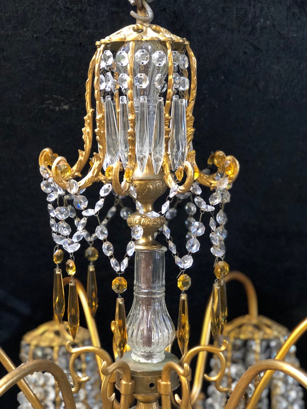 An Italian gilt-brass chandelier featuring multiple scrolling arms draped with crystal-beaded pod shades and amber glass drops. View II