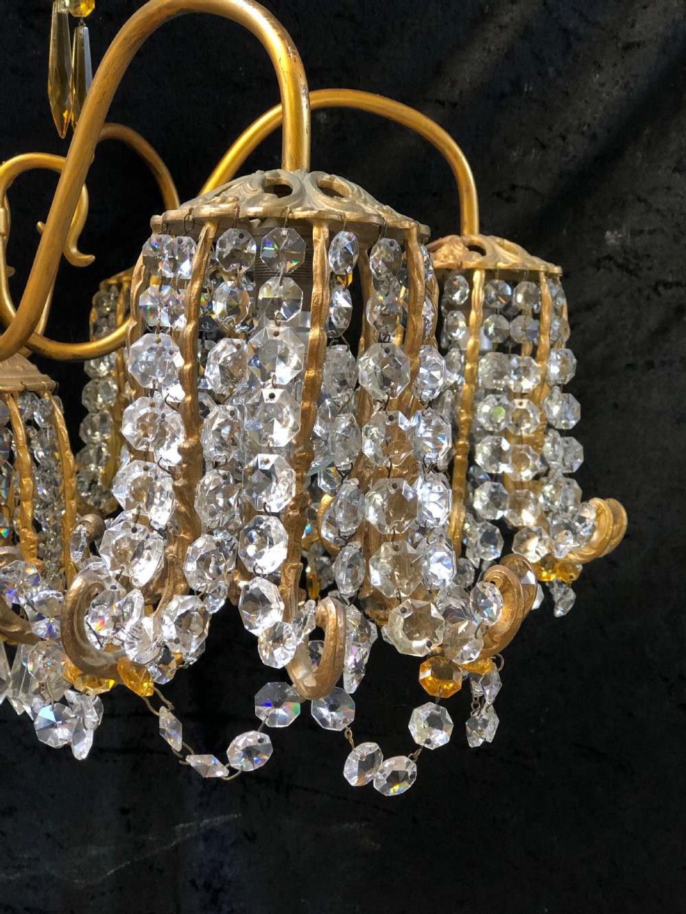 An Italian gilt-brass chandelier featuring multiple scrolling arms draped with crystal-beaded pod shades and amber glass drops. View V