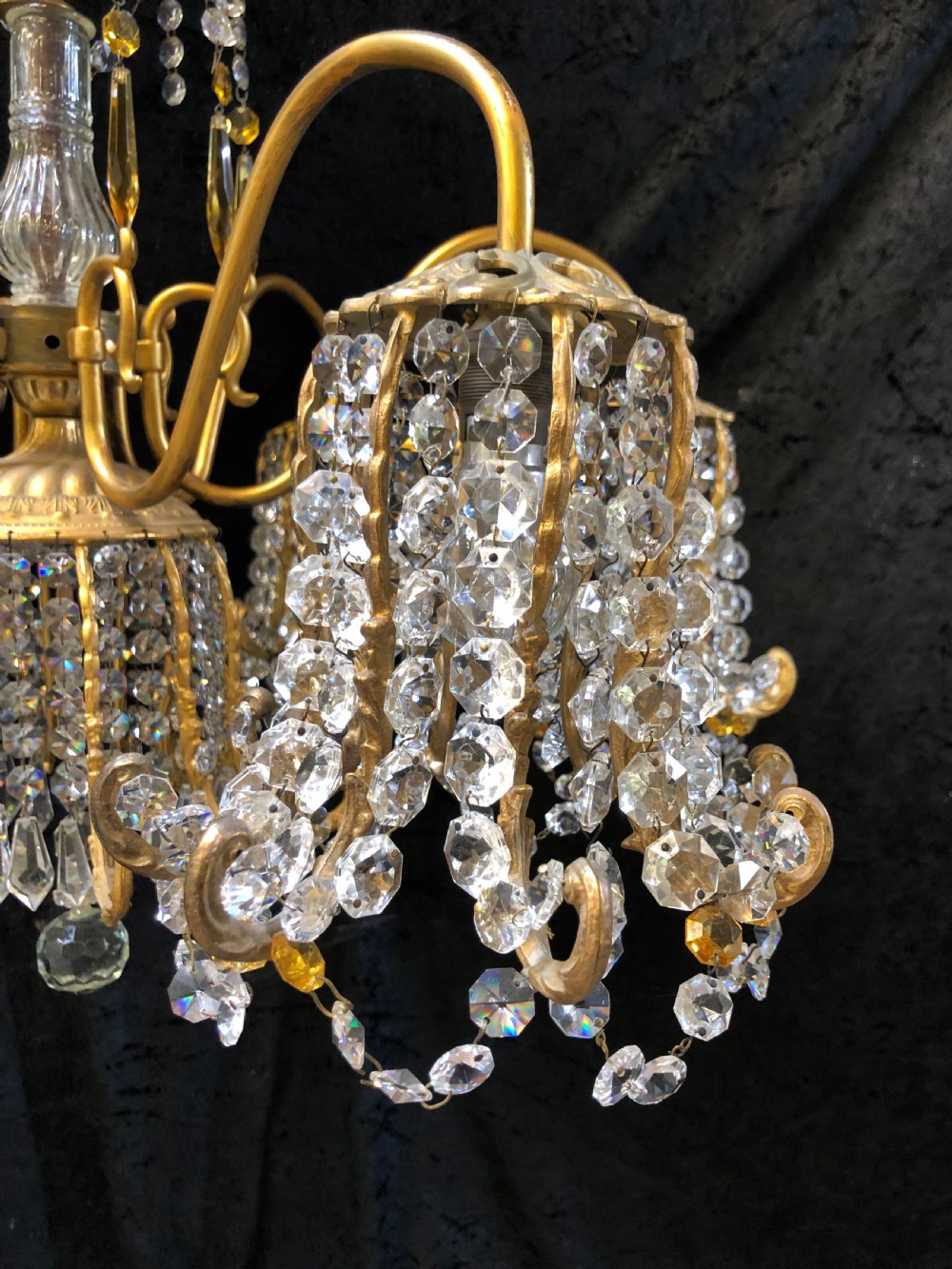 An Italian gilt-brass chandelier featuring multiple scrolling arms draped with crystal-beaded pod shades and amber glass drops. View VIII