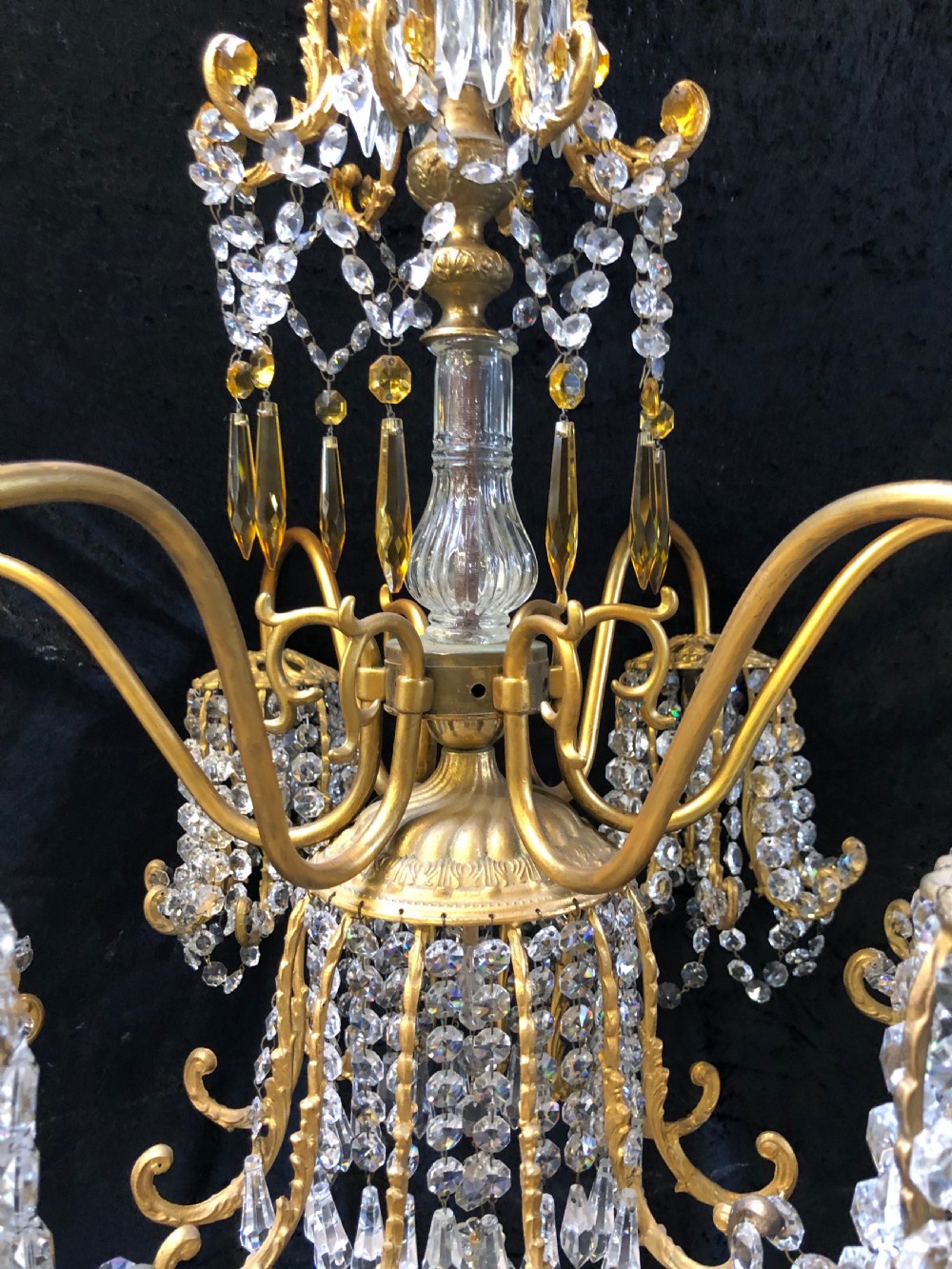 An Italian gilt-brass chandelier featuring multiple scrolling arms draped with crystal-beaded pod shades and amber glass drops. View IX