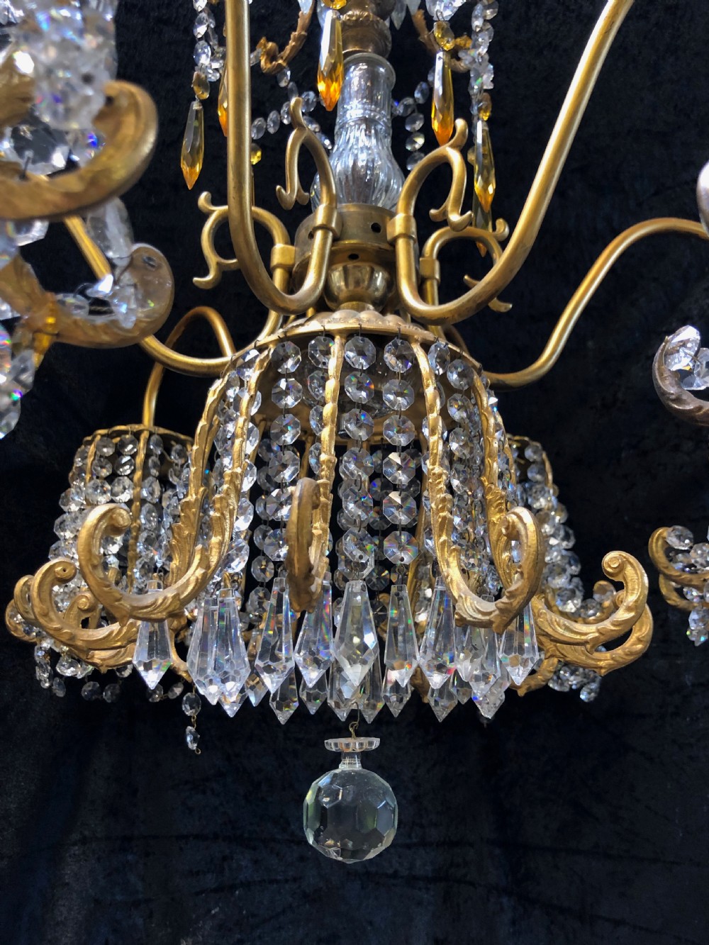 An Italian gilt-brass chandelier featuring multiple scrolling arms draped with crystal-beaded pod shades and amber glass drops. View X