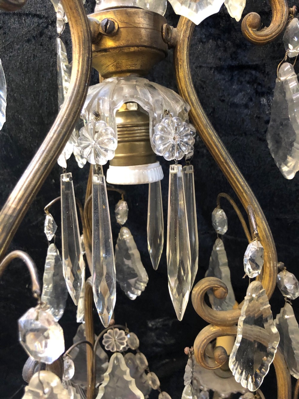 An antique French nine-light chandelier featuring a gilt metal frame dressed with clear faceted cut-glass crystals and pendeloque drops. View V