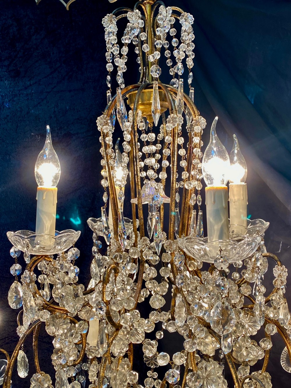 A twelve-light Florentine style chandelier featuring a gilded metal frame draped with clear faceted crystal beads and teardrop pendeloques. View II