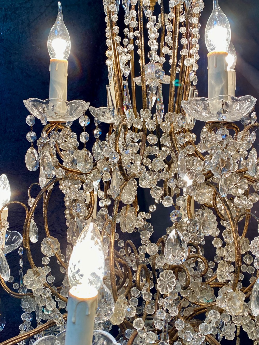 A twelve-light Florentine style chandelier featuring a gilded metal frame draped with clear faceted crystal beads and teardrop pendeloques. View III
