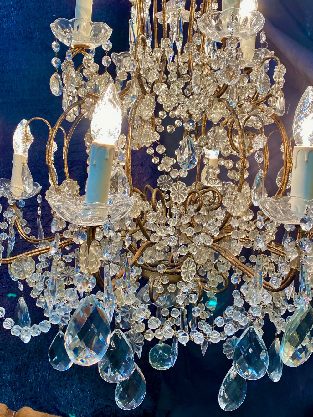 A twelve-light Florentine style chandelier featuring a gilded metal frame draped with clear faceted crystal beads and teardrop pendeloques. View IV