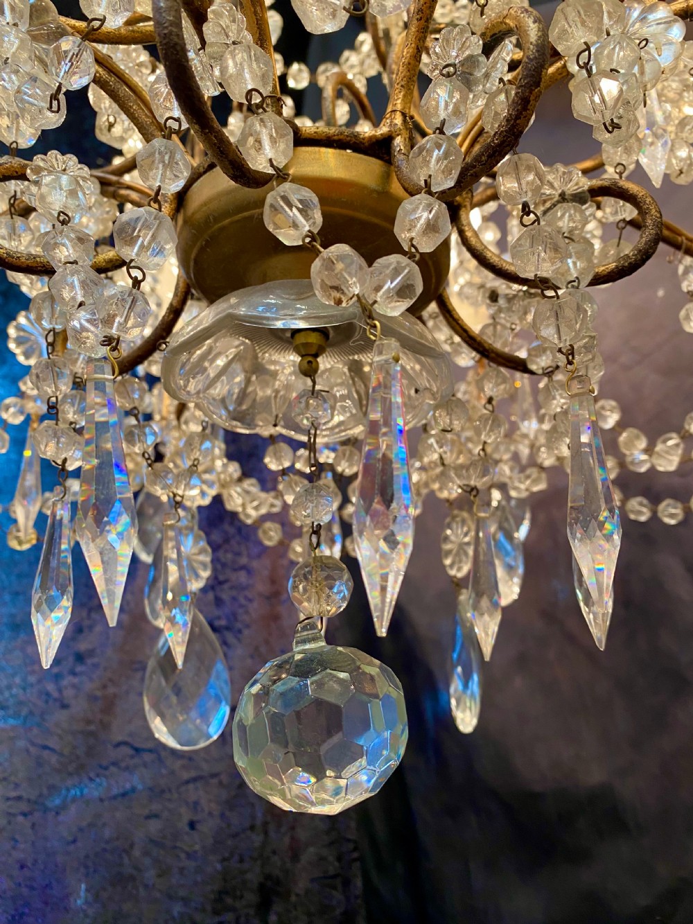 A twelve-light Florentine style chandelier featuring a gilded metal frame draped with clear faceted crystal beads and teardrop pendeloques. View VI