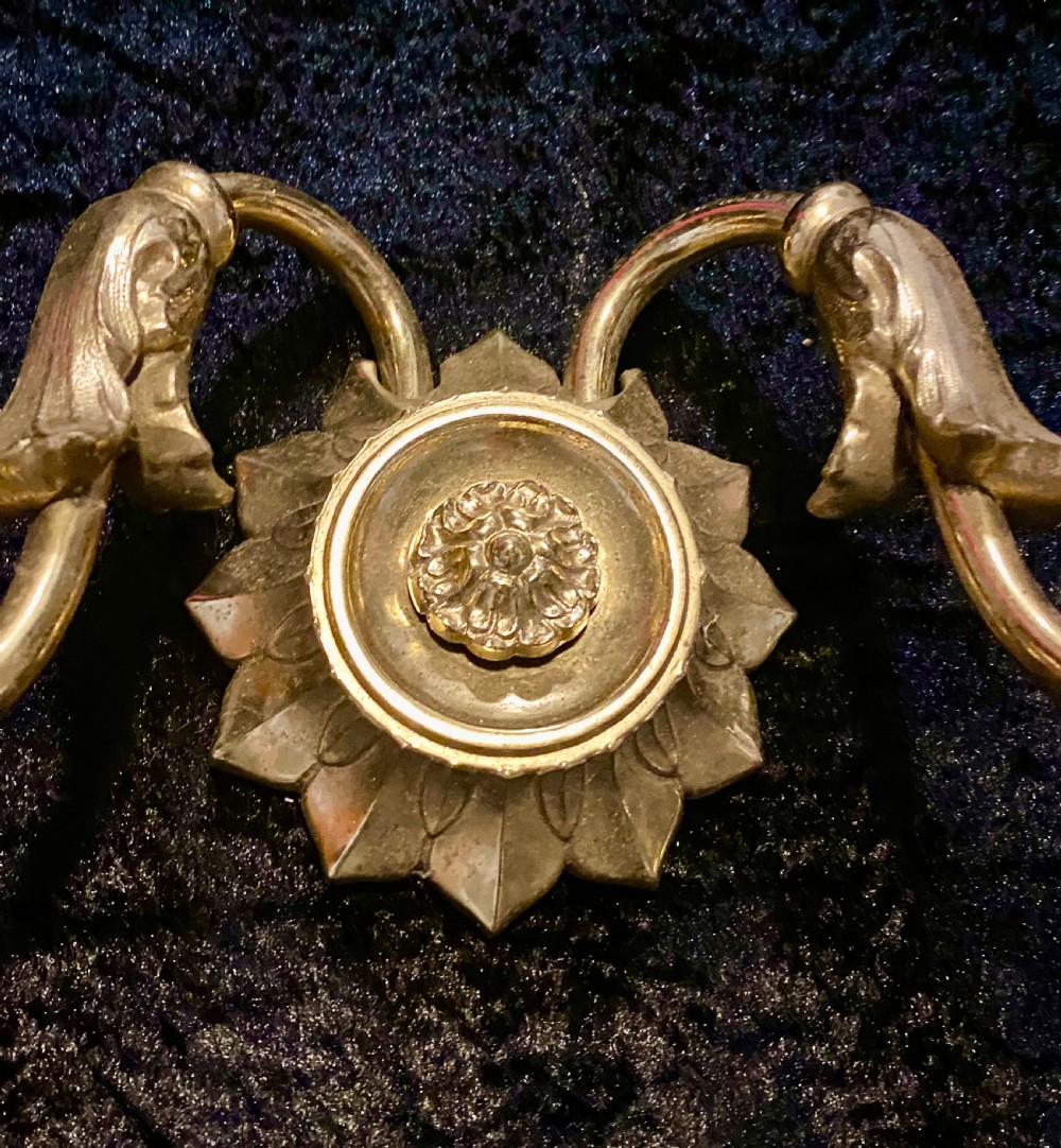 A pair of cast brass two-light wall sconces featuring sunburst backplates and curved acanthus leaf arms. View VIII
