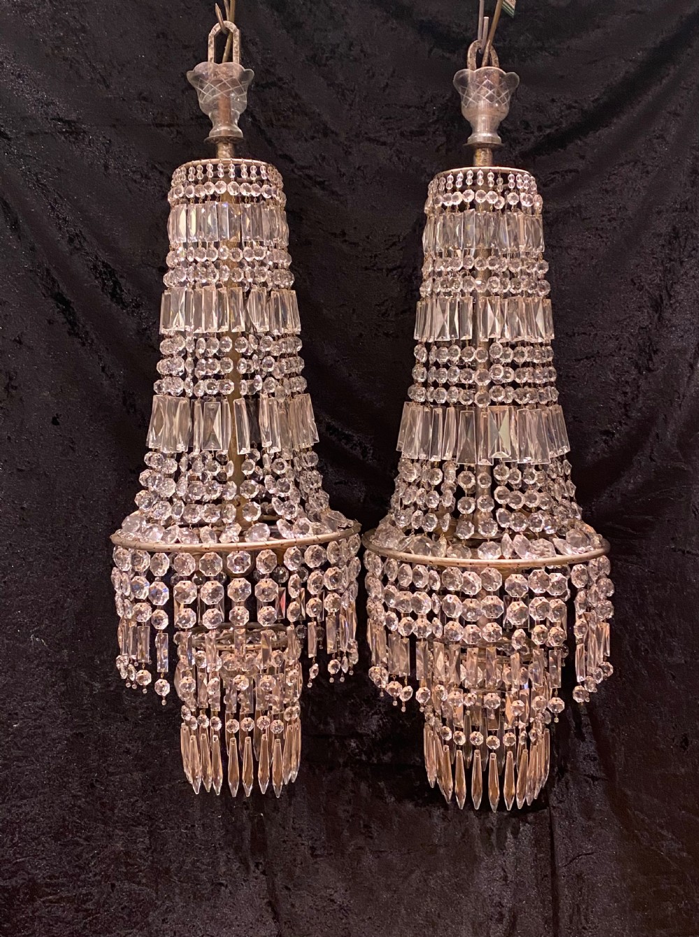 A pair of antique French tent and waterfall crystal chandeliers featuring concentric bands of cut glass prisms and octagonal beads suspended from metal hanging rings.