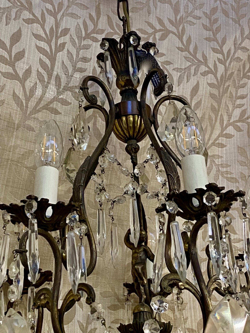 An Italian dark brass five-light chandelier adorned with crystal drops and a central metal cherub figurine. View II