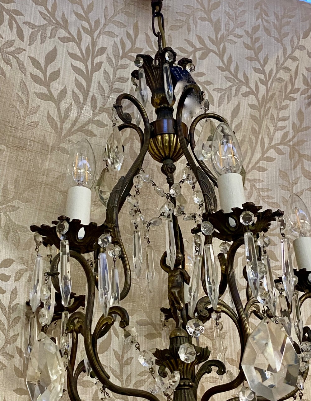 An Italian dark brass five-light chandelier adorned with crystal drops and a central metal cherub figurine. View III