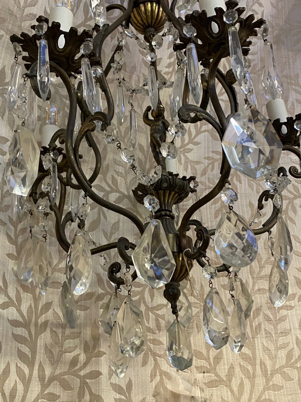 An Italian dark brass five-light chandelier adorned with crystal drops and a central metal cherub figurine. View IX
