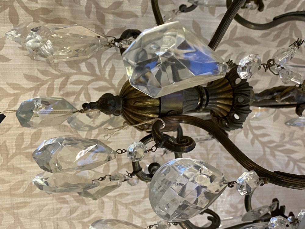 An Italian dark brass five-light chandelier adorned with crystal drops and a central metal cherub figurine. View X