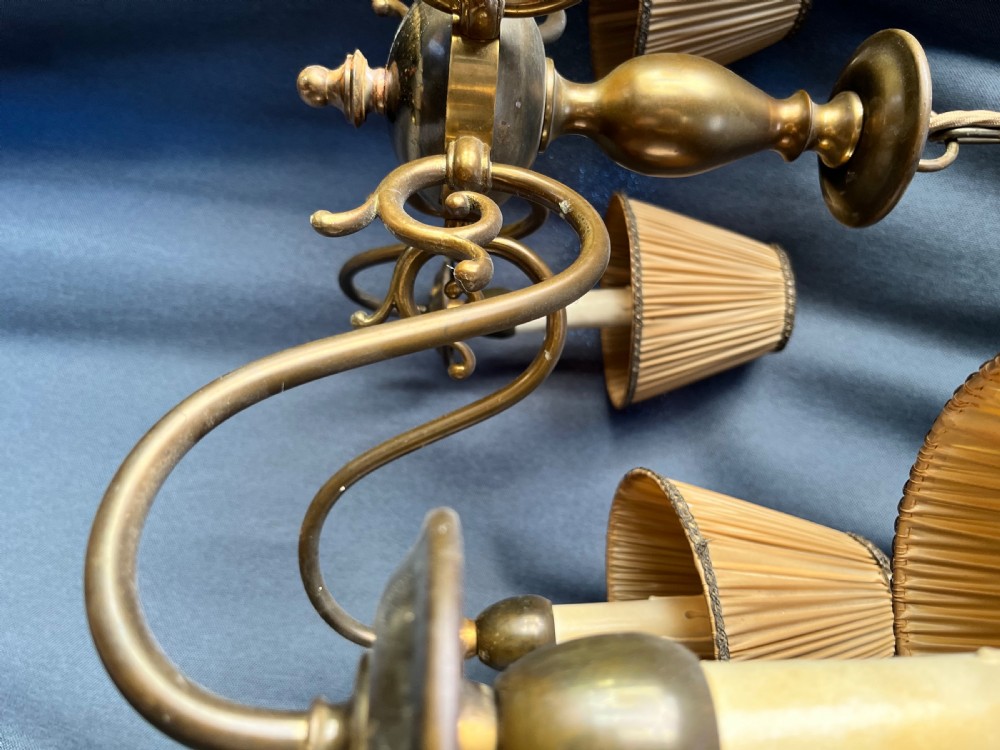 A six-arm brass Dutch pendant chandelier featuring a turned central baluster stem, scrolled arms, drip pans, and candle sleeves. View II