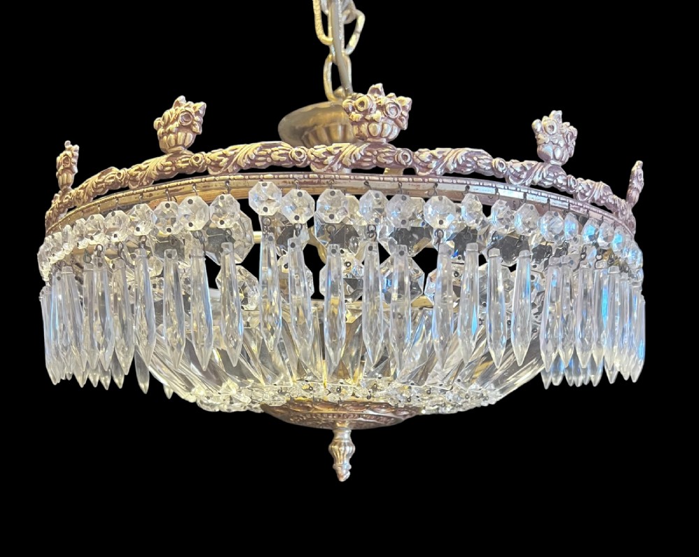 An antique French brass and cut crystal four-light plafoniere ceiling fixture featuring a decorated metallic rim with prism crystal drops and a central glass dish.