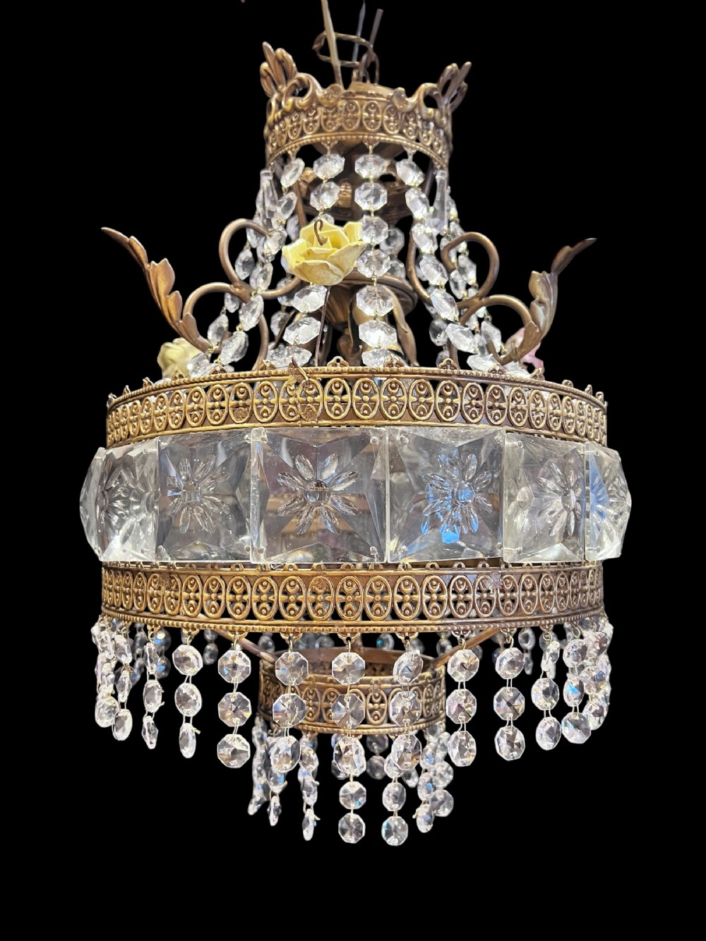 An antique Italian brass three-light chandelier decorated with square cut glass panels, hanging crystal bead strands, and yellow porcelain flowers.