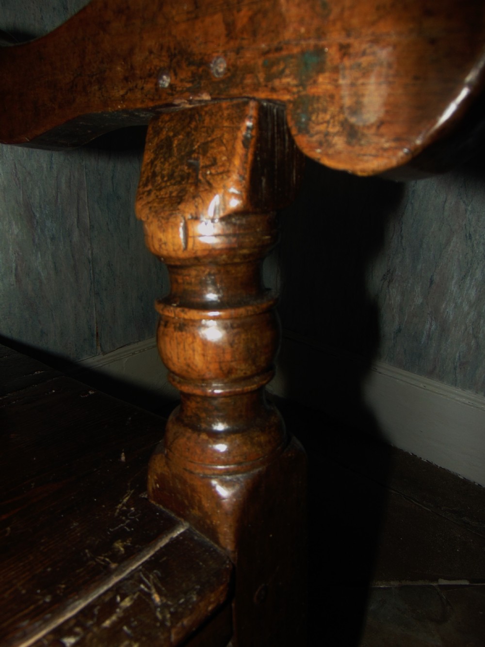 A late 17th-century dark oak settle featuring a carved high back, panelled frame, shaped armrests, and turned legs connected by stretchers. View IX