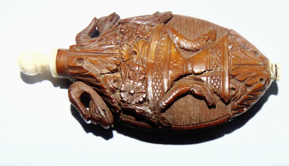 An oval carved coquilla nut scent bottle with a floral basket motif in relief and turned bone fittings at either end. View II