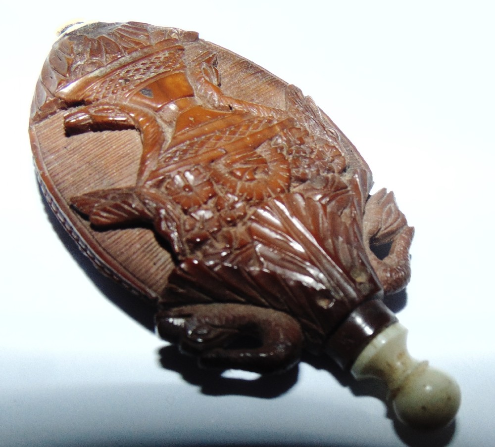 An oval carved coquilla nut scent bottle with a floral basket motif in relief and turned bone fittings at either end. View III