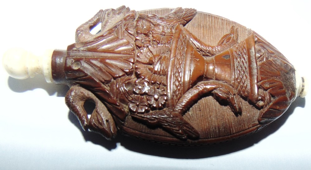 An oval carved coquilla nut scent bottle with a floral basket motif in relief and turned bone fittings at either end. View IV