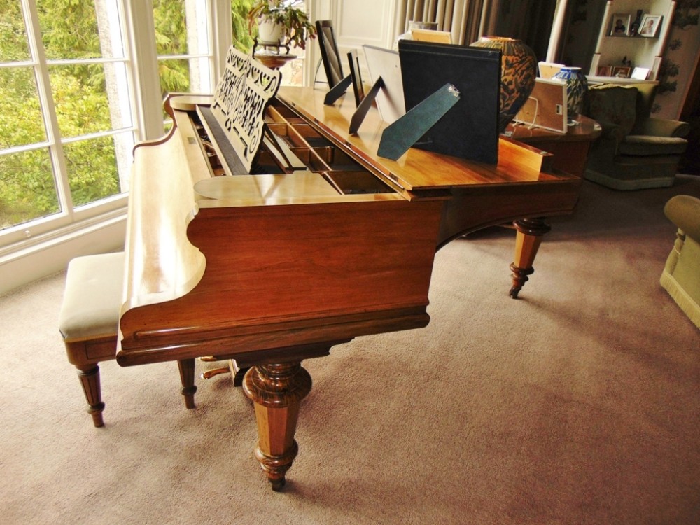 A late Victorian Bechstein grand piano in a figured rosewood case with an ornate carved fretwork music desk and turned legs on brass castors.