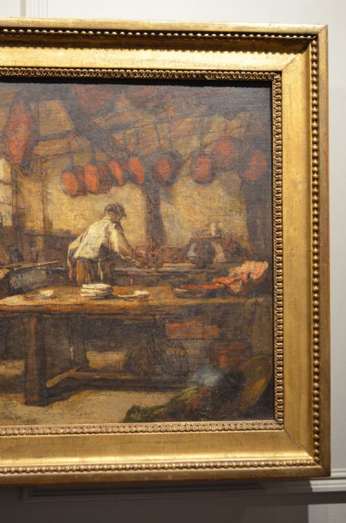 fig 1. A 19th-century framed oil painting depicting a rustic interior scene with a figure near a table amidst hanging items.