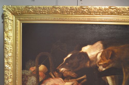 fig 2. An oil painting depicting two dogs reaching into a woven basket containing meat and fruit, encased in an ornate gilded frame.