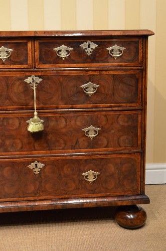 fig 2. An antique William and Mary period walnut chest of drawers featuring geometric oyster veneer patterns, brass teardrop handles, keyhole escutcheons, and turned bun feet.