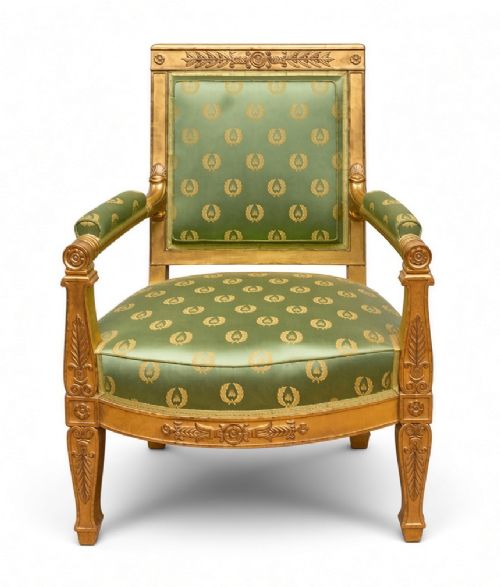 A French Restauration giltwood armchair with green and gold pattern silk upholstery, padded arms, and carved leaf detailing.