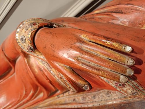 fig 3. A 19th-century Burmese carved wooden sculpture of a reclining Buddha featuring red lacquered finish and detailed gilded robes.