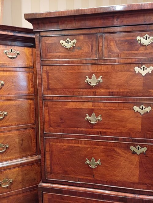 fig 3. An early eighteenth-century walnut chest on chest featuring crossbanded drawers, brass handles, and bracket feet.