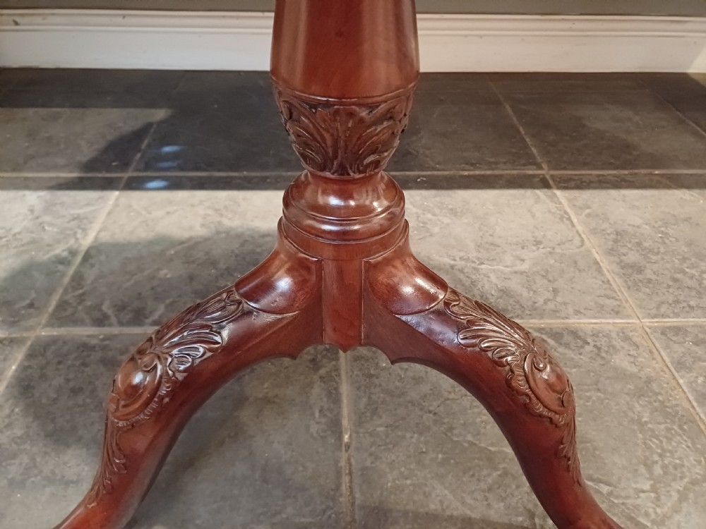 An 18th-century mahogany tilt-top table positioned vertically to display a carved piecrust border, turned pillar, and tripod cabriole legs. View VIII