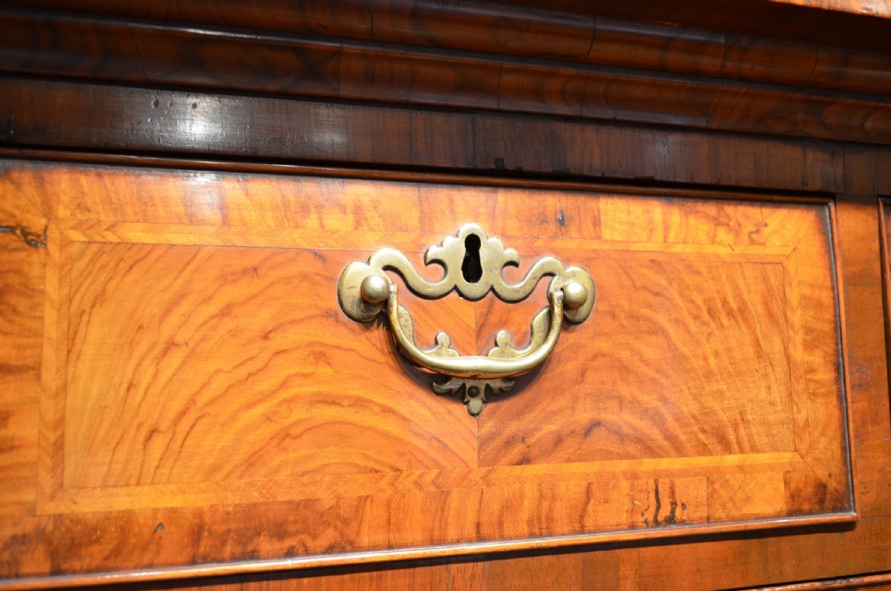 An 18th-century George I walnut chest on chest featuring tiered drawers with brass handles, featherbanded veneer, and bracket feet. View VIII
