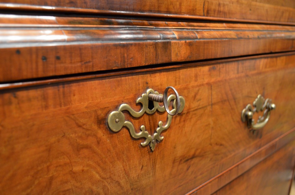 An 18th-century George I walnut chest on chest featuring tiered drawers with brass handles, featherbanded veneer, and bracket feet. View XVIII