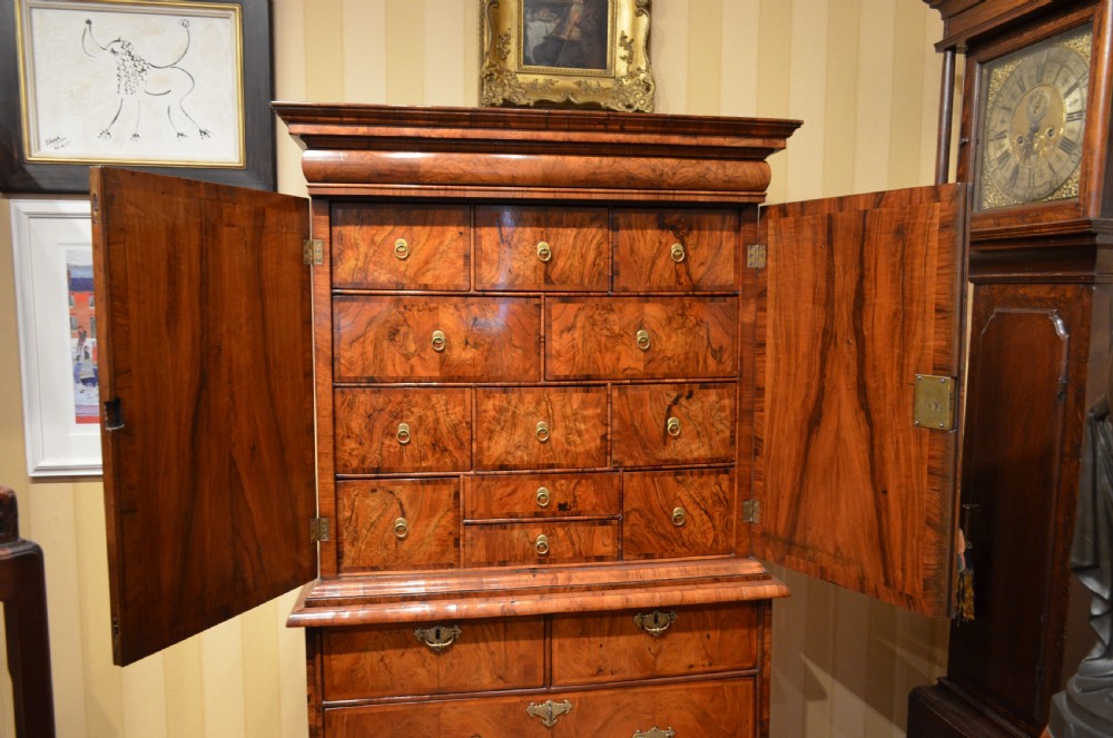 A two-section William and Mary walnut cabinet on chest featuring double doors with burr walnut panel veneers above a lower chest of drawers with turned bun feet. View XI