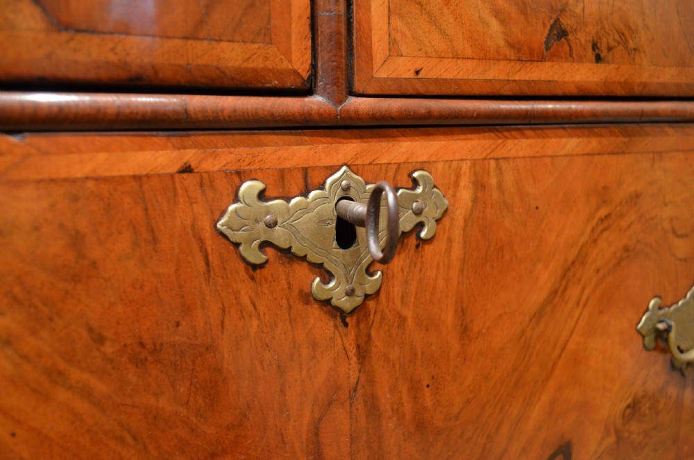 A two-section William and Mary walnut cabinet on chest featuring double doors with burr walnut panel veneers above a lower chest of drawers with turned bun feet. View XVII