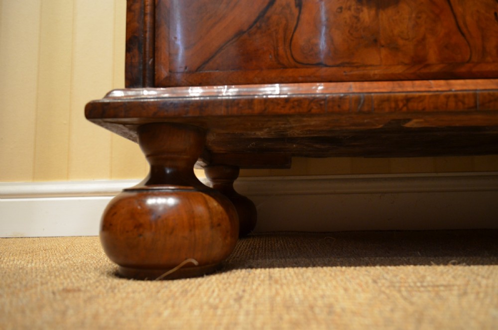 A two-section William and Mary walnut cabinet on chest featuring double doors with burr walnut panel veneers above a lower chest of drawers with turned bun feet. View XXI