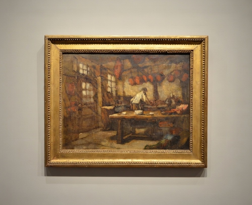 A 19th-century framed oil painting depicting a rustic interior scene with a figure near a table amidst hanging items.