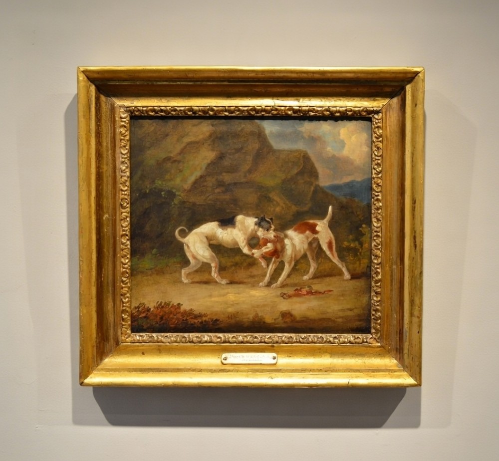 An 19th-century oil painting depicting two sporting dogs in an outdoor landscape, enclosed within a heavy carved gilded frame.