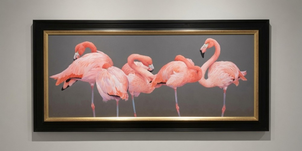 A wide panoramic oil painting on board depicting five pink flamingos in detailed poses against a grey background, encased in a black and gilt wooden frame.