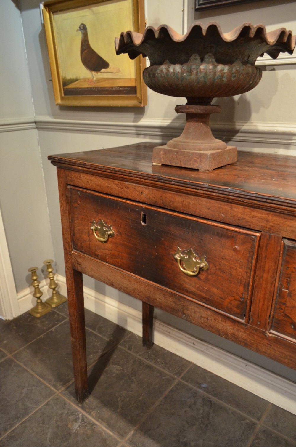 A Georgian solid oak dresser base featuring three drawers with brass swan-neck handles, supported by four straight square legs. View V