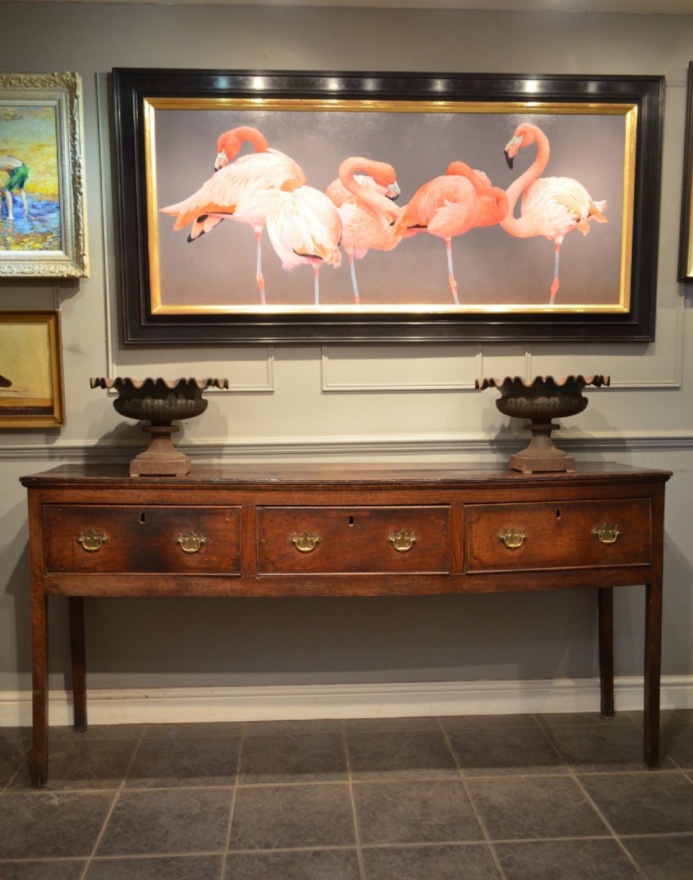 A Georgian solid oak dresser base featuring three drawers with brass swan-neck handles, supported by four straight square legs. View VII