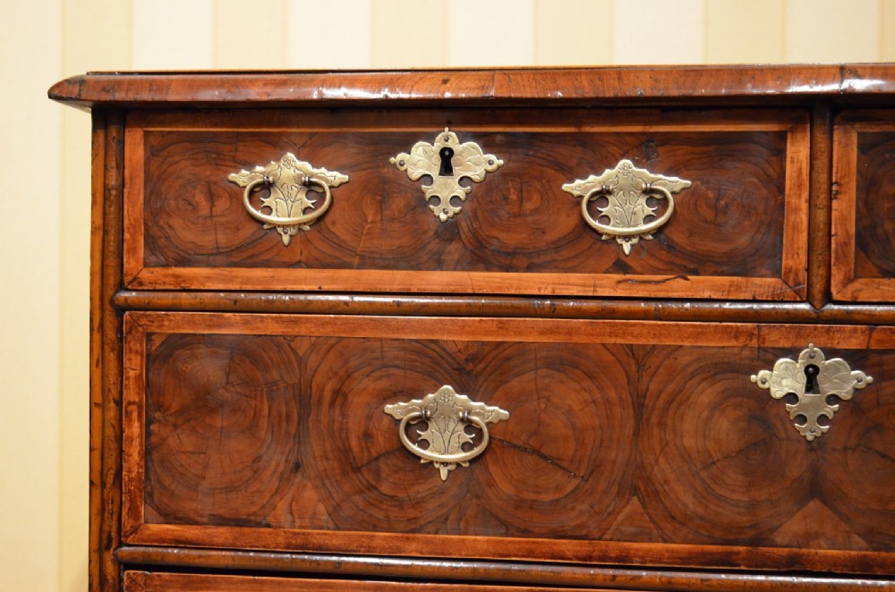 An antique William and Mary period walnut chest of drawers featuring geometric oyster veneer patterns, brass teardrop handles, keyhole escutcheons, and turned bun feet. View IV