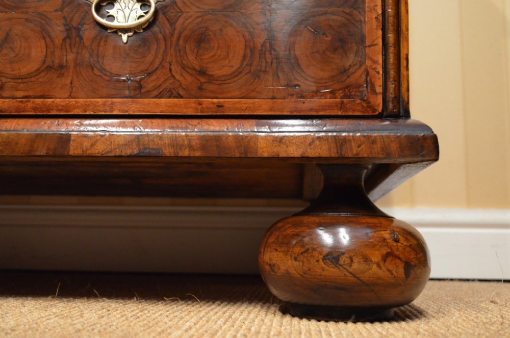 An antique William and Mary period walnut chest of drawers featuring geometric oyster veneer patterns, brass teardrop handles, keyhole escutcheons, and turned bun feet. View VI