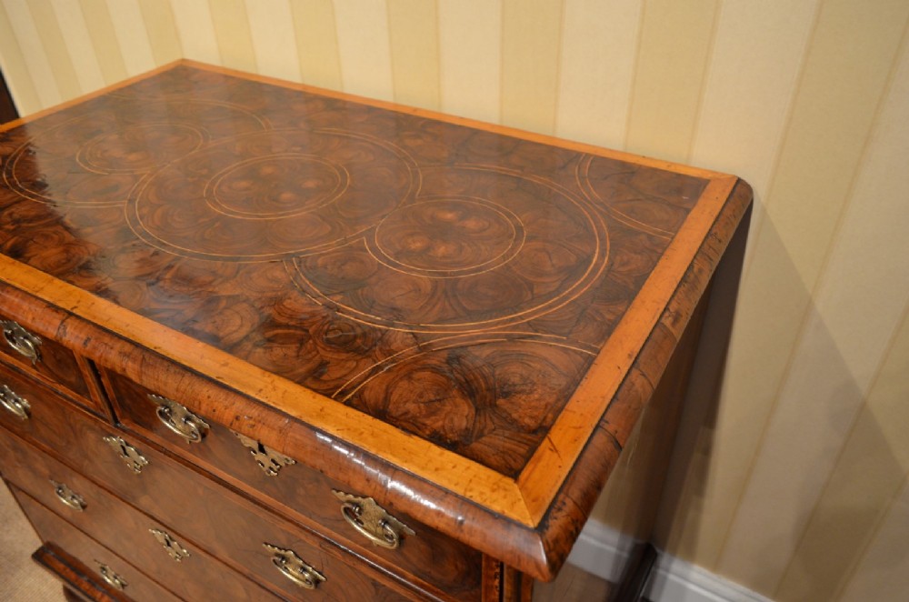 An antique William and Mary period walnut chest of drawers featuring geometric oyster veneer patterns, brass teardrop handles, keyhole escutcheons, and turned bun feet. View VIII