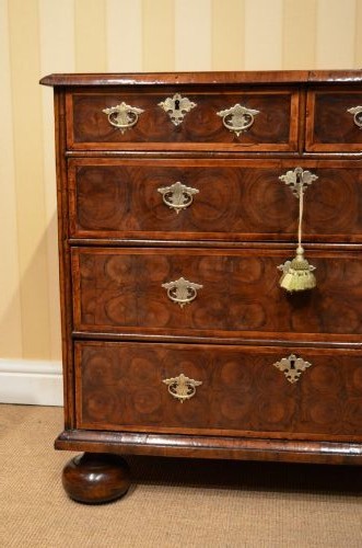 An antique William and Mary period walnut chest of drawers featuring geometric oyster veneer patterns, brass teardrop handles, keyhole escutcheons, and turned bun feet. View II