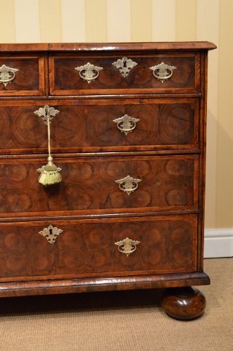 An antique William and Mary period walnut chest of drawers featuring geometric oyster veneer patterns, brass teardrop handles, keyhole escutcheons, and turned bun feet. View III