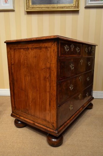 An antique William and Mary period walnut chest of drawers featuring geometric oyster veneer patterns, brass teardrop handles, keyhole escutcheons, and turned bun feet. View IX