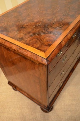 An antique William and Mary period walnut chest of drawers featuring geometric oyster veneer patterns, brass teardrop handles, keyhole escutcheons, and turned bun feet. View X